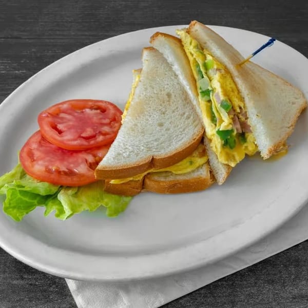 JJ Cafe's breakfast egg sandwich with lettuce and tomato slices on a white plate.