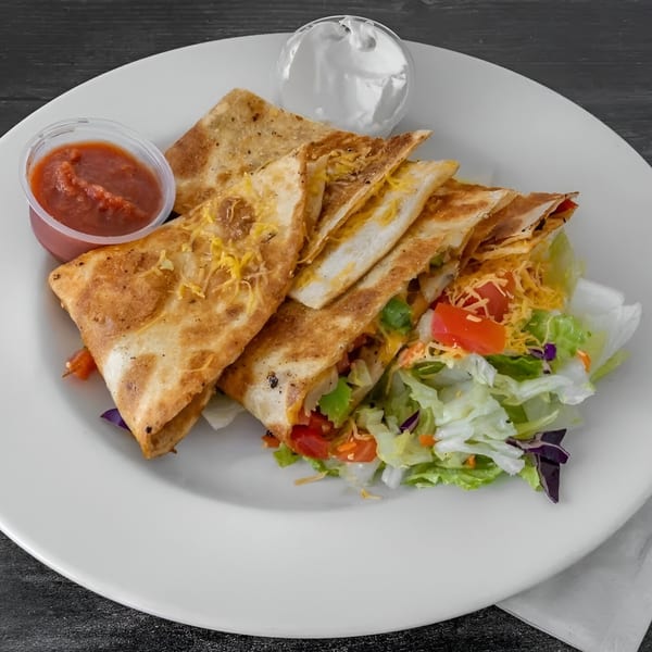 JJ Cafe's breakfast quesadillas with salsa, sour cream, and a side salad on a white plate.