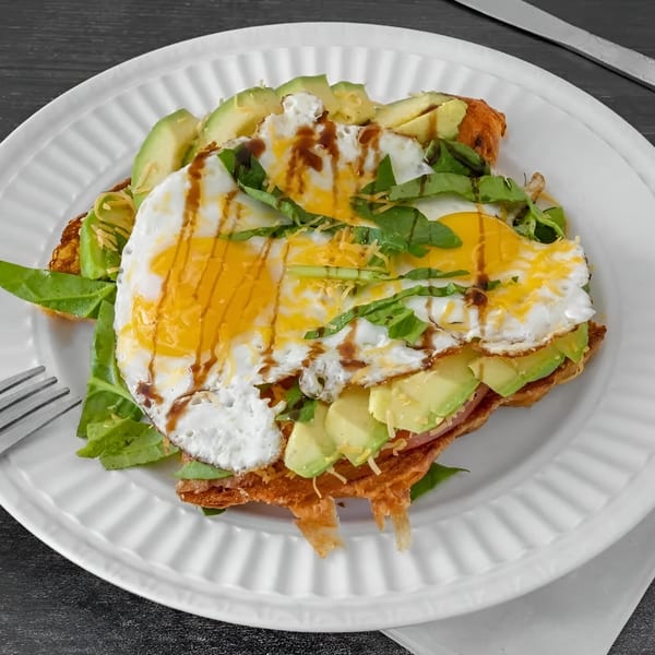 JJ Cafe's breakfast dish with fried eggs, avocado, greens, and sauce on a waffle.